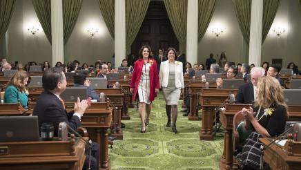 Asm. Aguiar-Curry escorts 2017 Woman of the Year Award Elizabeth Van de Leur Alessio to the front of the chamber